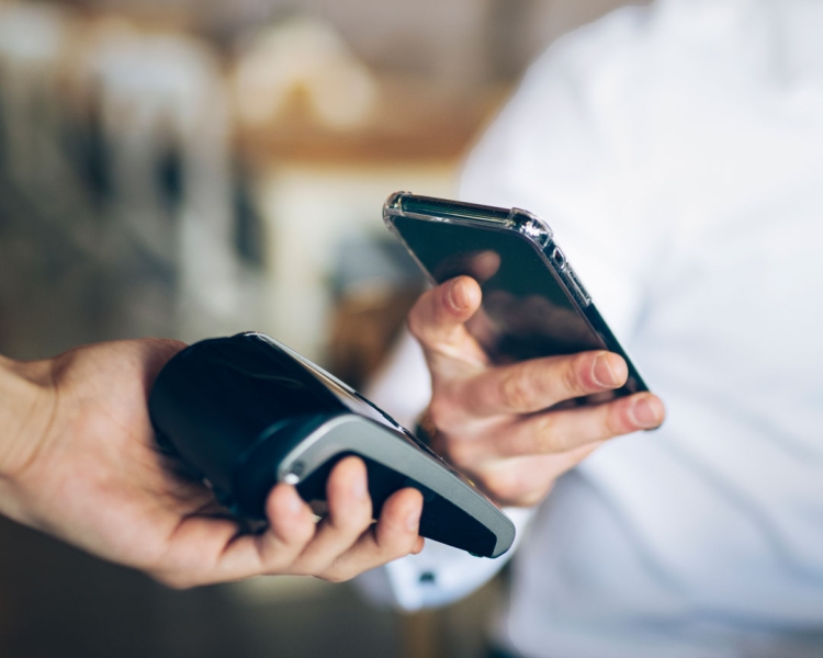 Ein Mann bezahlt mit dem Smartphone kontaktlos