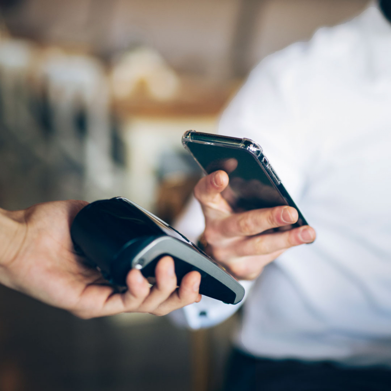 Ein Mann bezahlt mit dem Smartphone kontaktlos