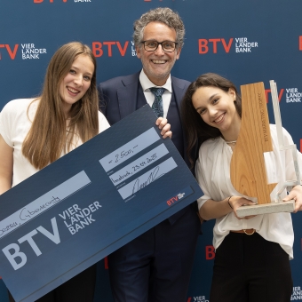 3 Personen halten einen Preis in der Hand