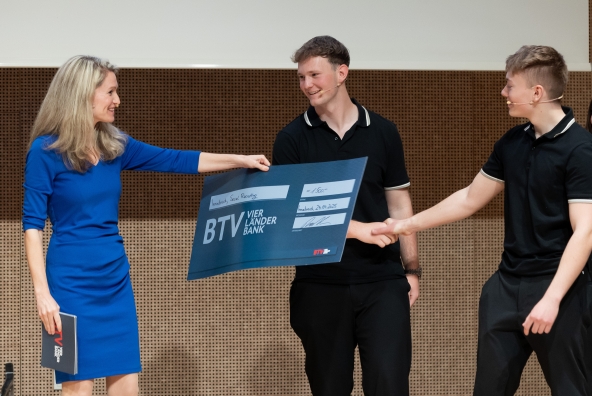 Drei Personen halten einen Preis in der Hand
