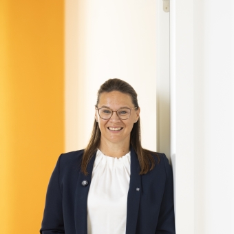 Ein Frau steht in einer Türöffnung und trägt einen blauen Blazer