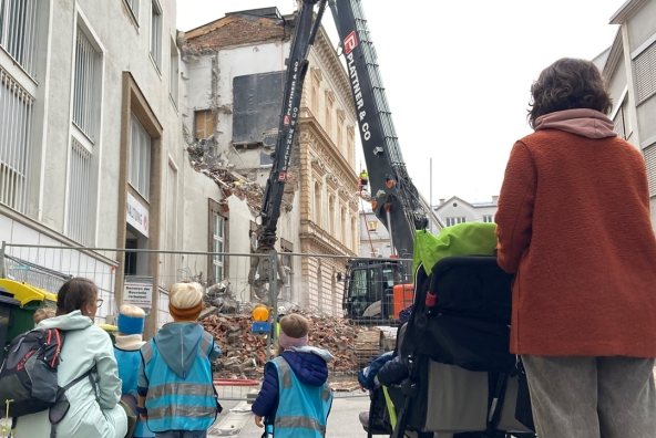 Zwei Erwachsene und mehrere Kinder schauen auf eine Ruine