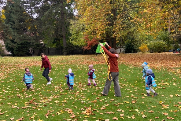 Zwei Frauen spielen mit Kinder auf einer Wiese im Park