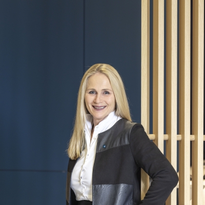 Monika Reichart-Michler, Betreuung Retail Banking der BTV Bregenz, steht in einer Bankfiliale vor einer Holzwand.