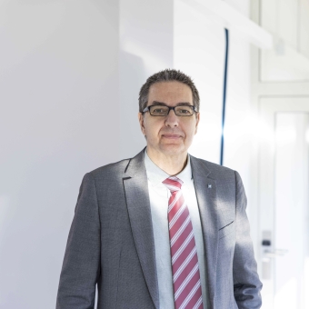 Michael Bodner, Experte für Vorsorge & Versicherungen der BTV, steht in einer Bankfiliale und trägt einen grauen Anzug.