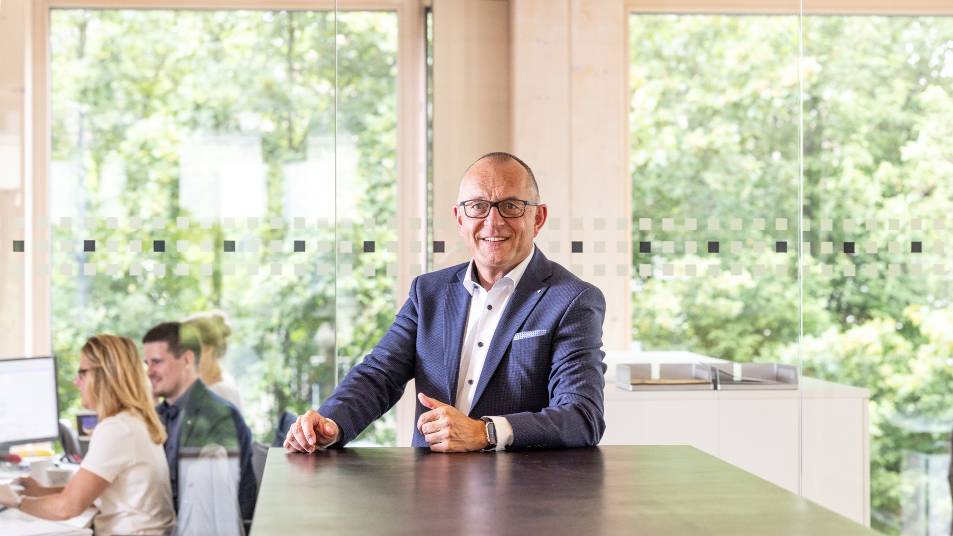 Ein Mann steht an einem Stehtisch und trägt eine Brille