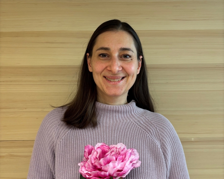 Eine Frau trägt einen Wollpullover und hält eine Blume in der Hand.