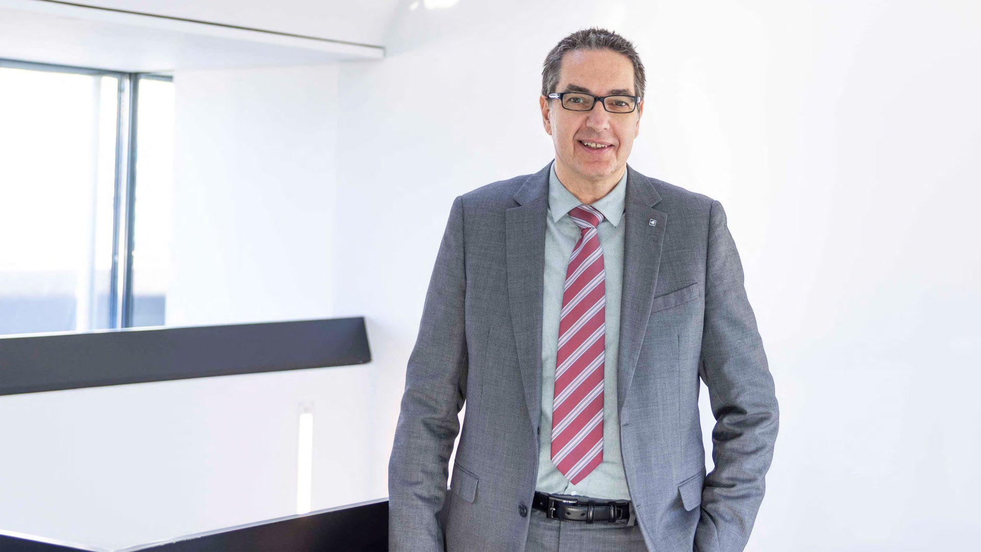 Michael Bodner, Experte für Vorsorge & Versicherungen der BTV, steht in einer Bankfiliale und trägt einen grauen Anzug.