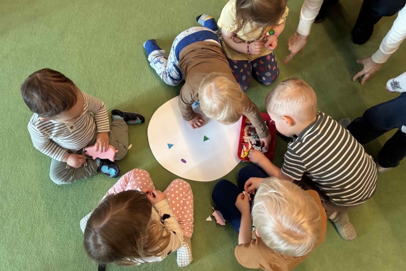 Kinder legen geometrische Formen auf eine Fläche