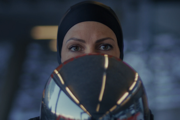 Janine Flock hält ihren Rennhelm und blickt in die Kamera