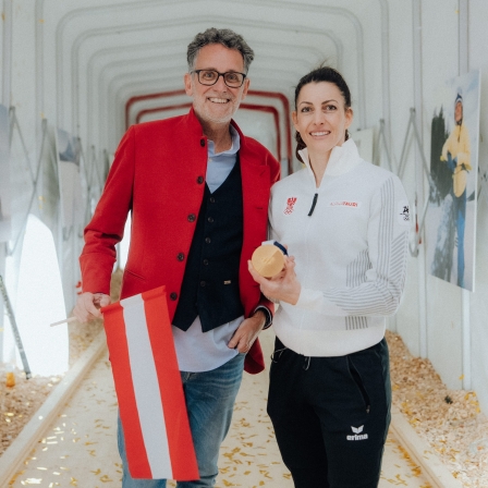 Gerhard Burtscher mit einer Österreich-Flagge und Janine Flock mit Goldmedaille