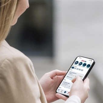 Frau hält Handy in der Hand. Auf dem Display ist ein Ausschnitt des Startbildschirms der BTV Banking App zu sehen.
