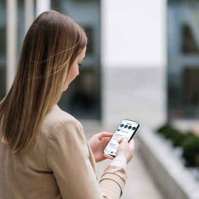 Frau hält Handy in der Hand. Auf dem Display ist ein Ausschnitt des Startbildschirms der BTV Banking App zu sehen.