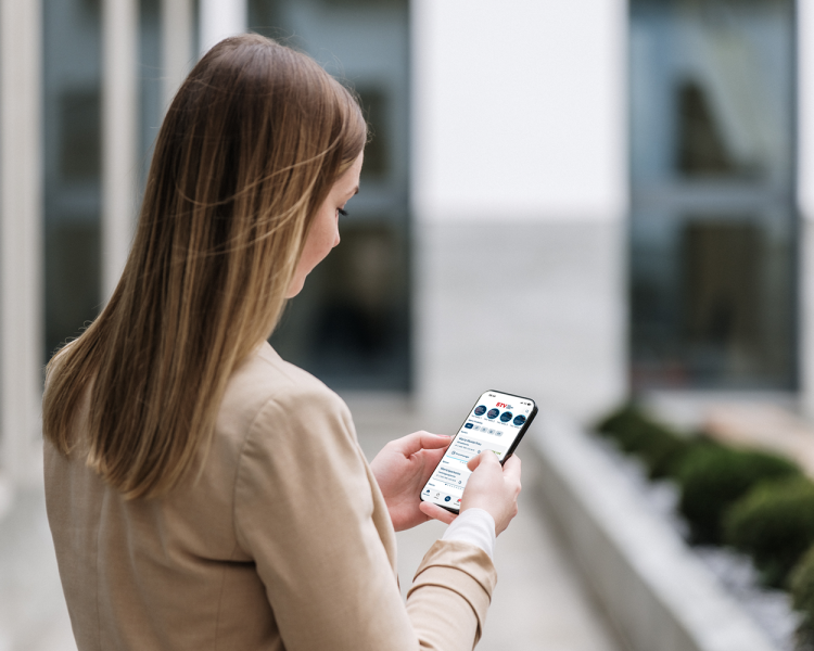 Frau hält Handy in der Hand. Auf dem Display ist ein Ausschnitt des Startbildschirms der BTV Banking App zu sehen.
