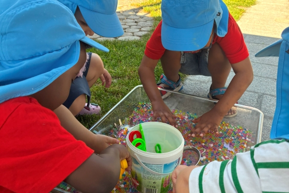 Mehrere Kinder sitzen am Boden der MUKKI Dornbirn Kinderkrippe und spielen mit Murmeln.