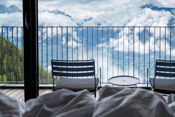 Sitzgelegenheit auf einem Balkon mit weitem Blick über eine alpine Berglandschaft.