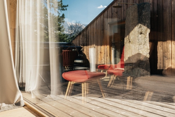Sitzgelegenheit in einem Hotelzimmer, im Fenster spiegelt sich die umliegende Landschaft.