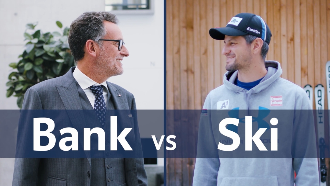 BTV Vorstandsvorsitzender Gerhard Burtscher und Skirennfahrer Johannes Strolz blicken einander an; im Vordergrund steht der Text „Bank vs Ski“.