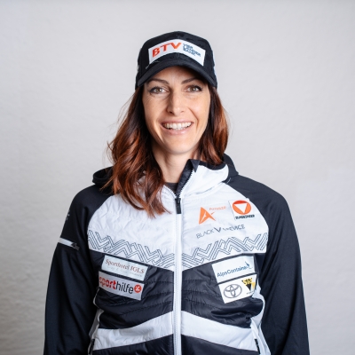 Skeletonpilotin Janine Flock posiert zum Kick‑off des Saisonsstarts 2025 und trägt dabei Sportkleidung ihrer Sponsoren.