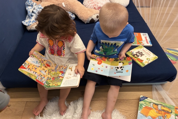 Kinder der MUKKI‑Kinderkrippe sehen sich verschiedene Kinderbücher an.