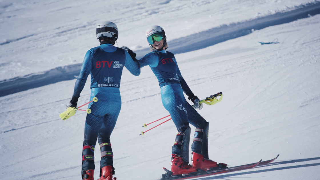 Marlies und Benni Raich stehen als BTV Markenbotschafter auf einer Skipiste und geben sich lächelnd die Hand.