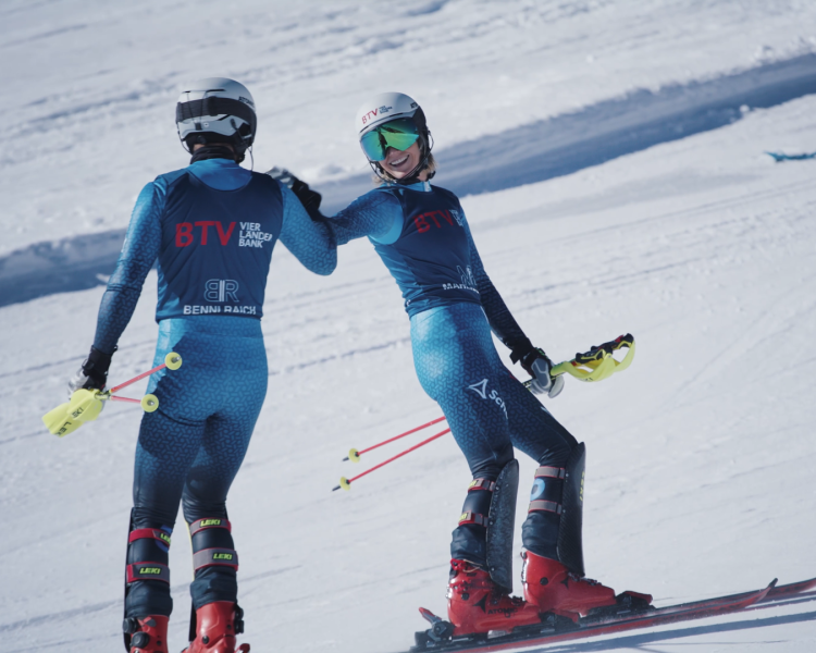 Marlies und Benni Raich stehen als BTV Markenbotschafter auf einer Skipiste und geben sich lächelnd die Hand.