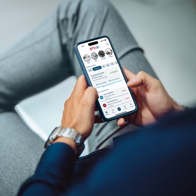 Hände halten ein Smartphone, auf dem die Oberfläche der BTV Banking App zu sehen ist.