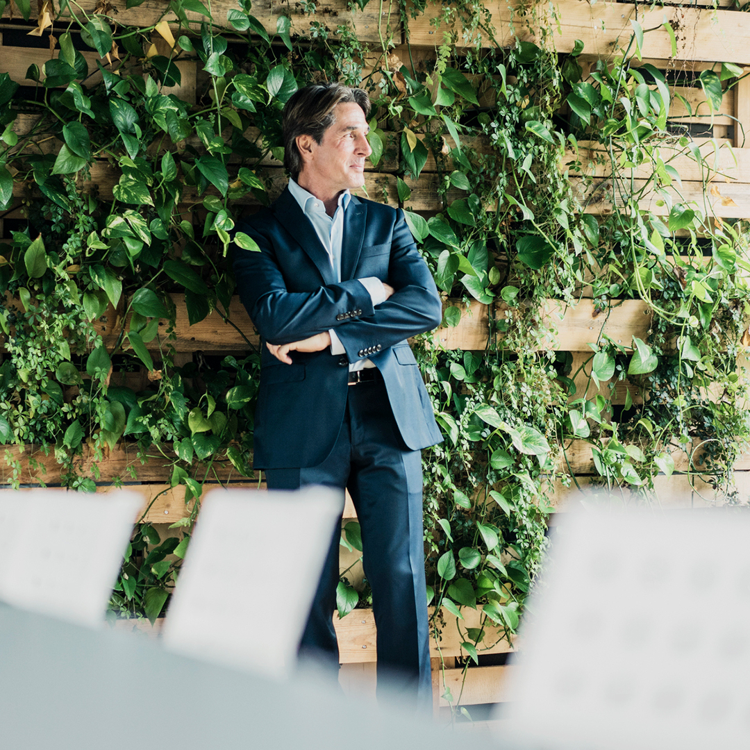 Businessmann vor einer Wand mit grünen Pflanzen