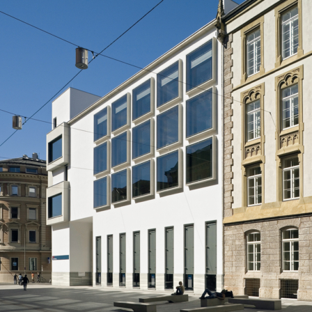 BTV Zentrale in Innsbruck Außenansicht: Weißes, modernes Gebäude mit vielen Fenstern zwischen zwei Altbau-Gebäuden
