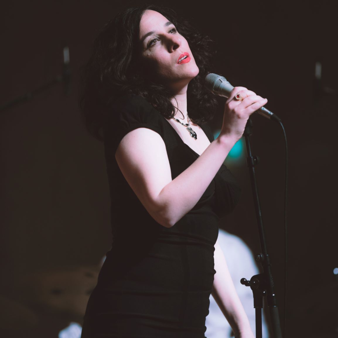 Eine Frau in schwarzem Kleid singt auf einer Bühne
