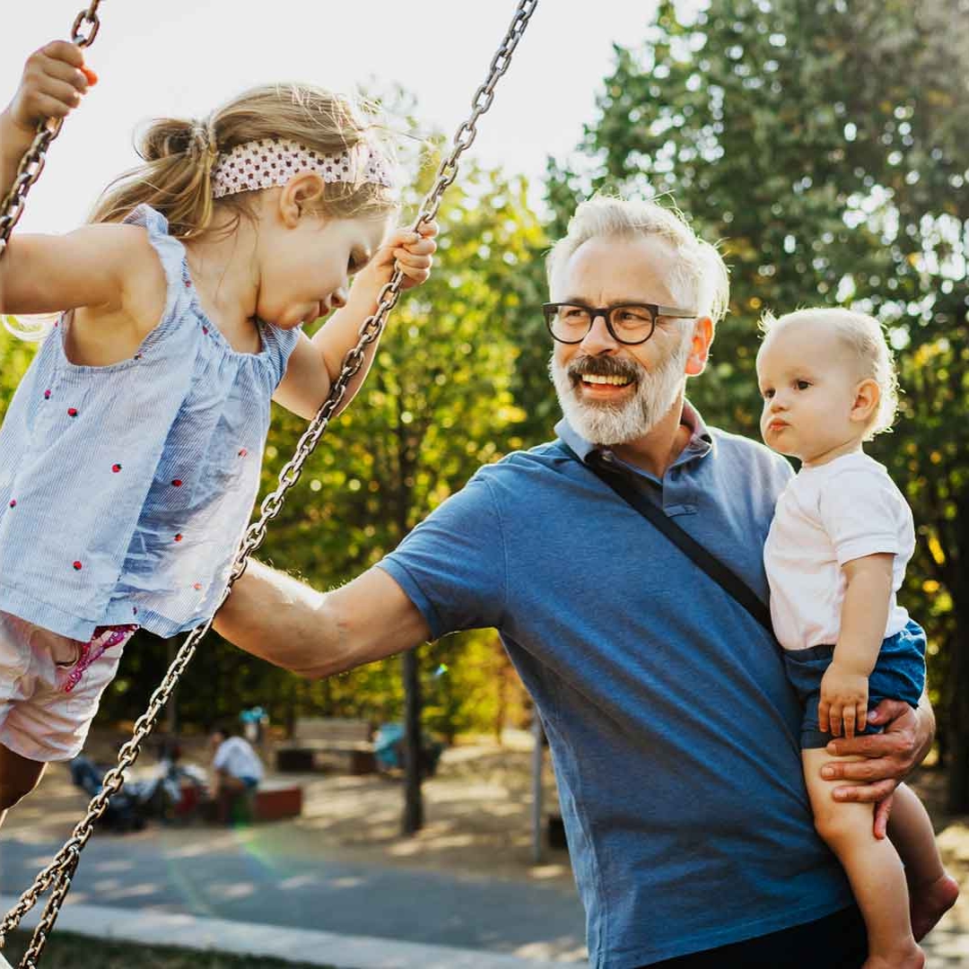 Mann mit seinen zwei Kindern am Spielplatz