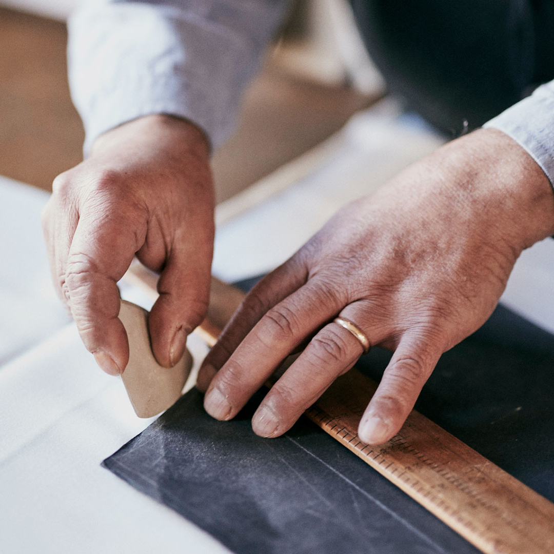 A man marks fabric with chalk and ruler