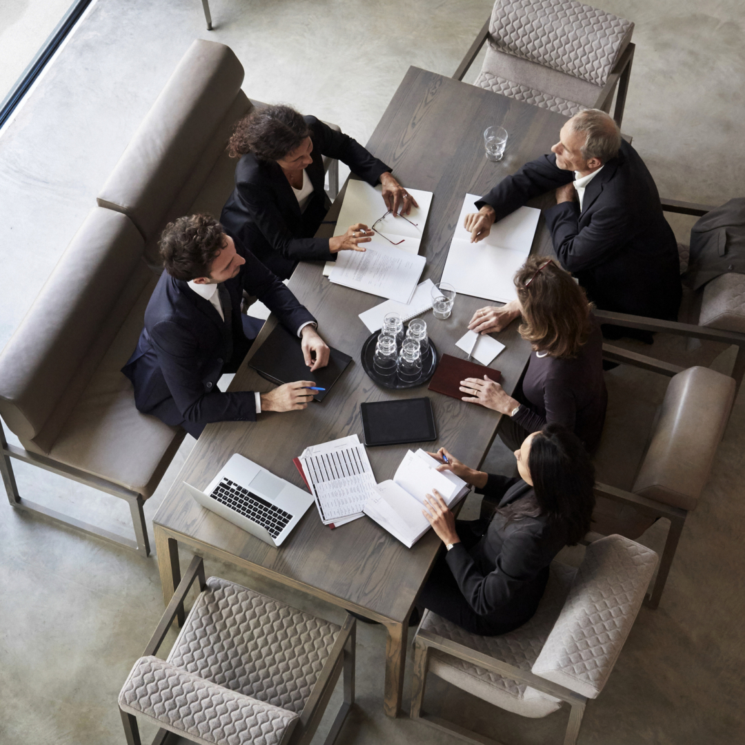 Fünf Geschäftsleute sitzen an einem Tisch zusammen und sprechen