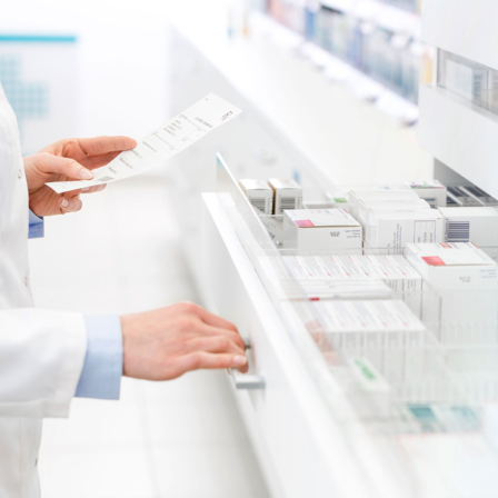 Pharmazeut öffnet Apothekenschrank mit Medikamenten