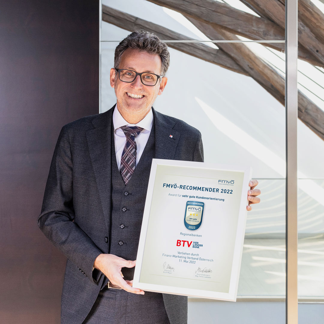 Gerhard Burtscher im Anzug hält die eingerahmte Auszeichnung FMVÖ-Recommender 2022 in den Händen