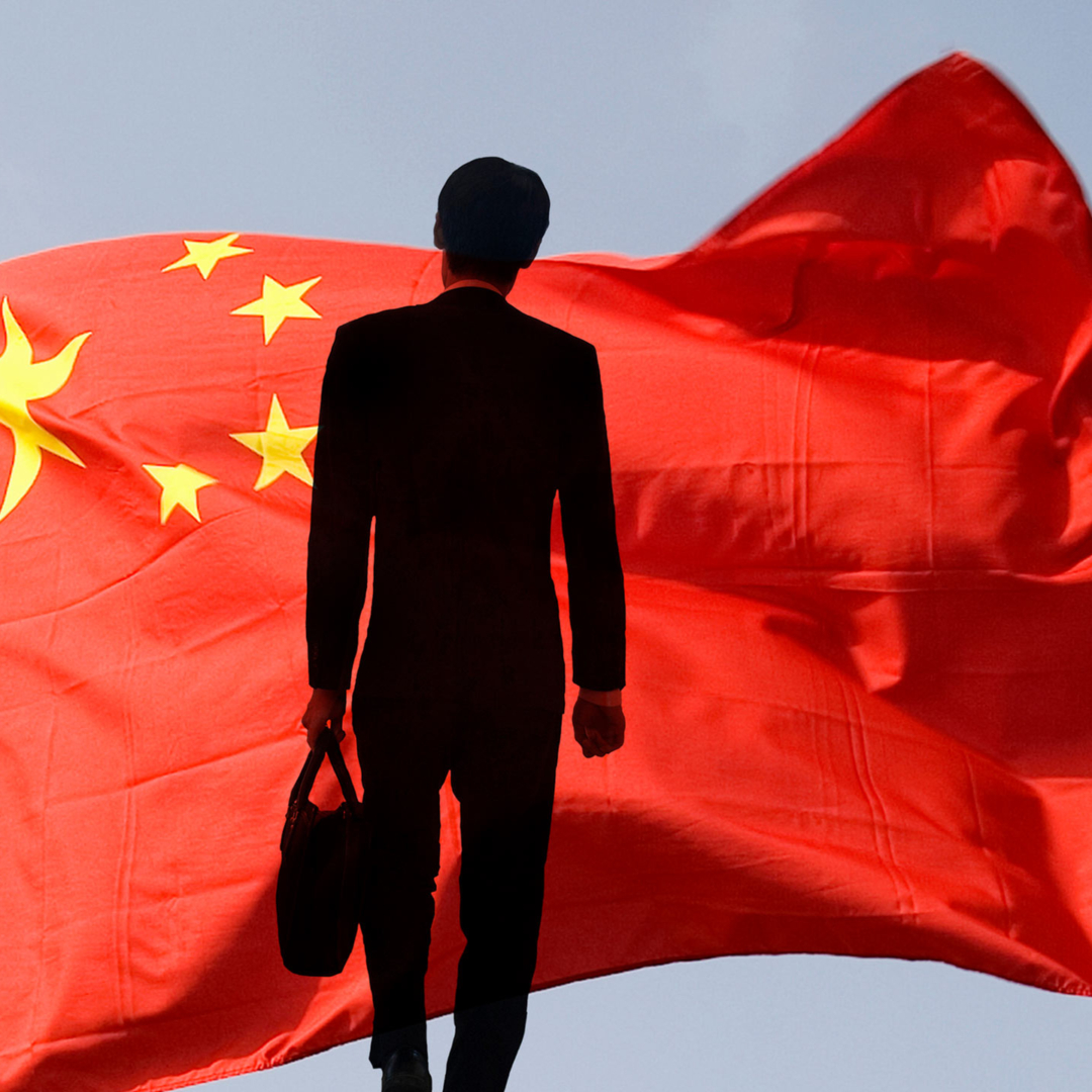 Ein Geschäftsmann steht vor einer chinesischen Flagge