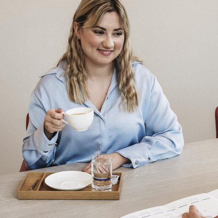 Ein Frau mit einer Tasse Kaffee spricht mit einem Mann.