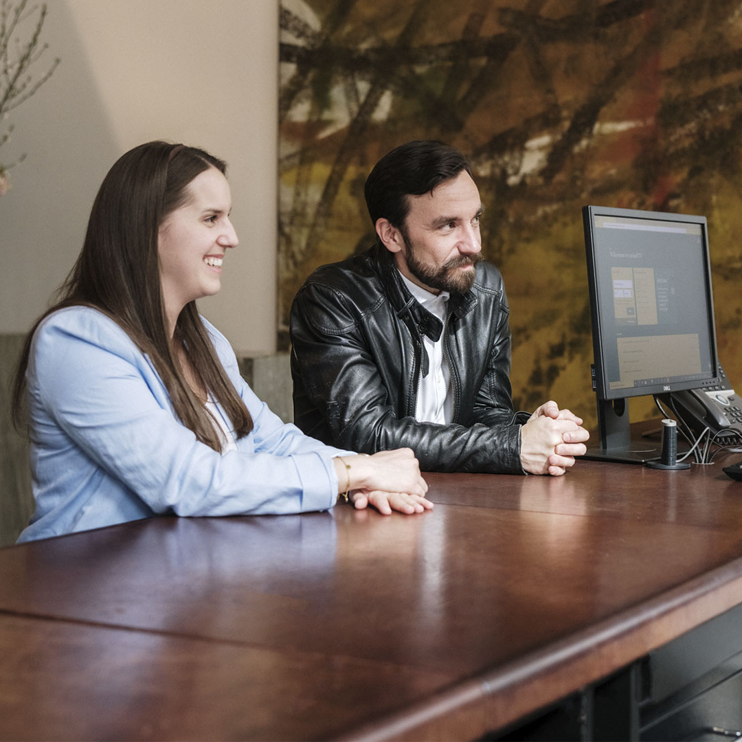 Zwei Personen lachen und unterhalten sich mit einer Bankmitarbeiterin.