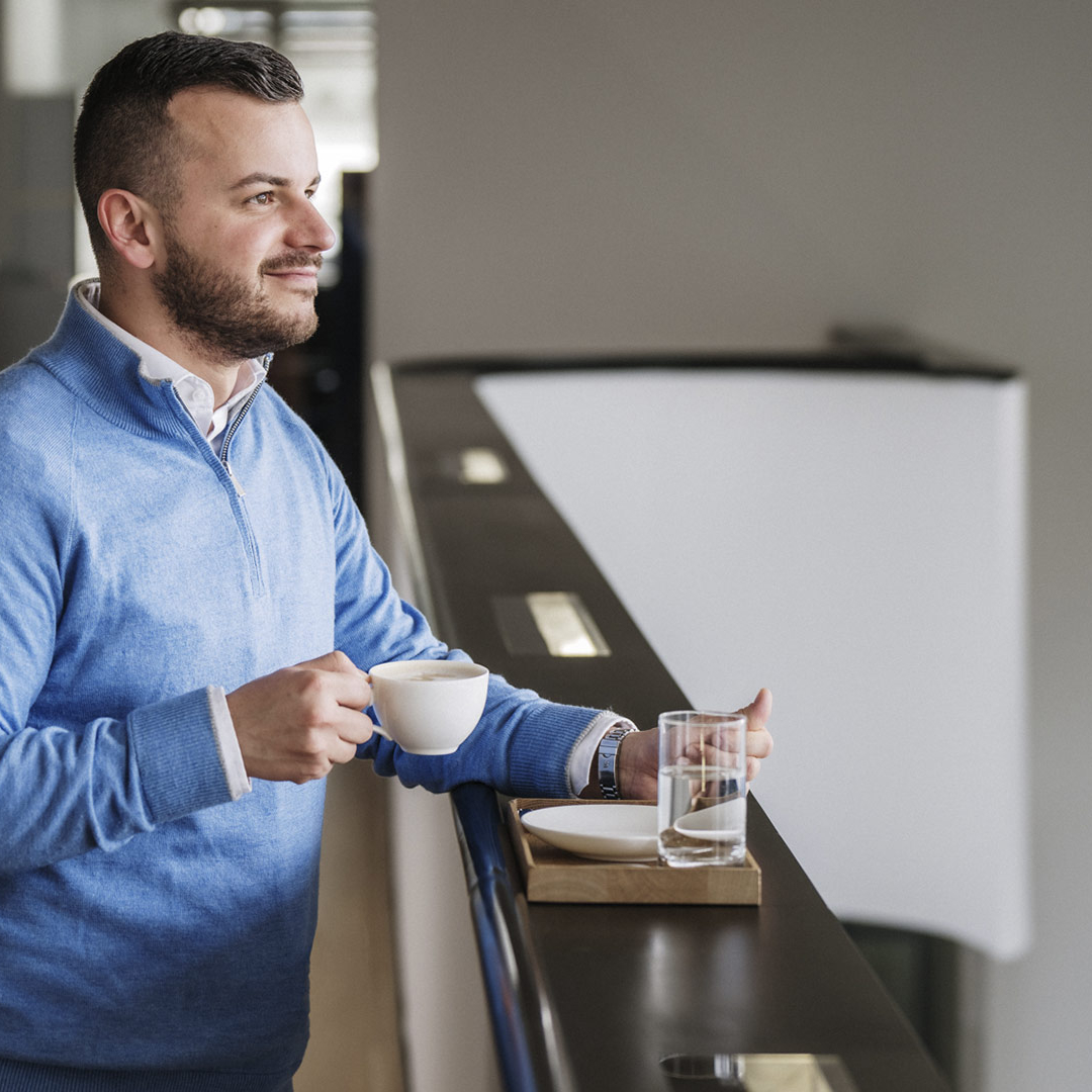 Ein Mann schaut in die Ferne und trinkt einen Kaffee.