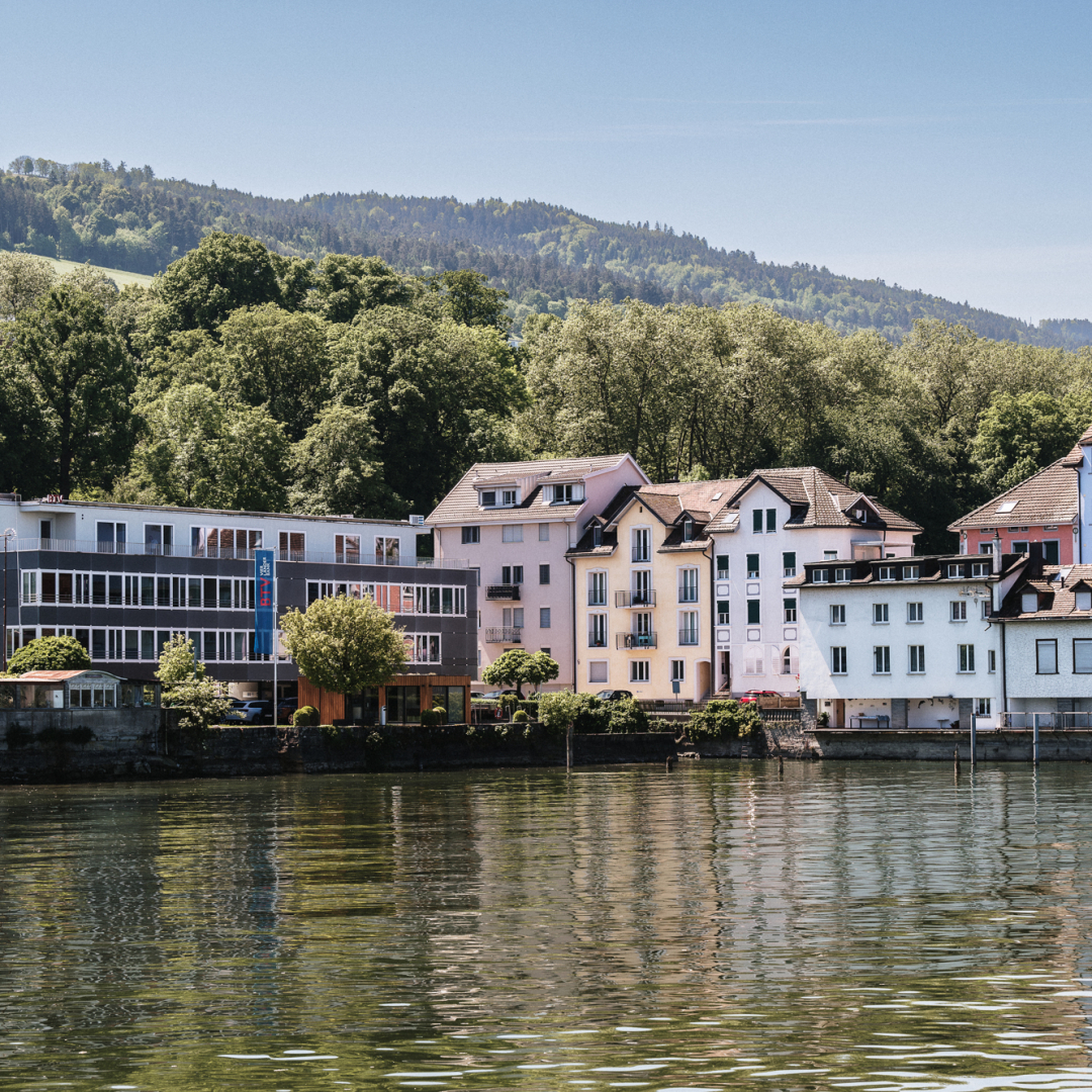 Ein See mit verschiedenste Häuserfassaden im Hintergrund.