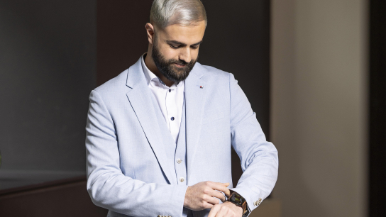 Ein Mann im blauen Anzug schaut auf seine Uhr